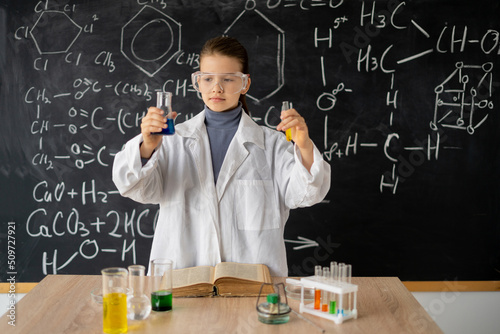 schoolgirl conducting chemistry experiment. little student on chemistry lesson in lab. science experiments in classroom activities