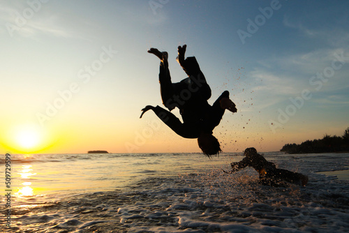 person jumping on the beach at sunset