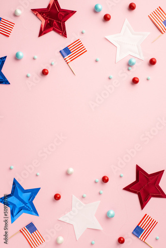 USA Independence Day concept. Top view vertical photo of US national flags star garland and scattered candies on isolated pastel pink background with copyspace