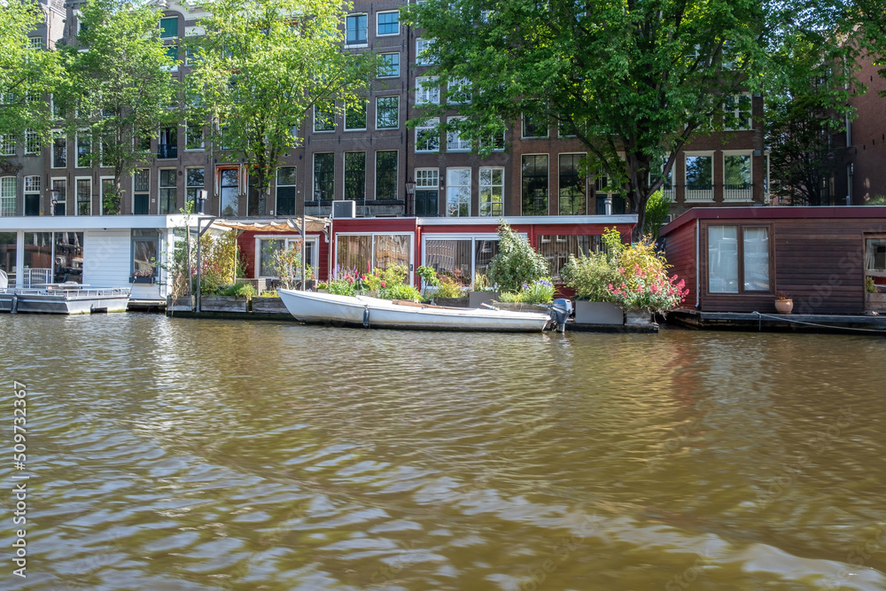 Obraz premium Houseboat in canal, Amsterdam. Boat and traditional house brick façade, parked bikes. Netherlands.