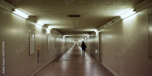 暗い長い地下道を一人で歩く女性　Woman walking alone in dark underground passage