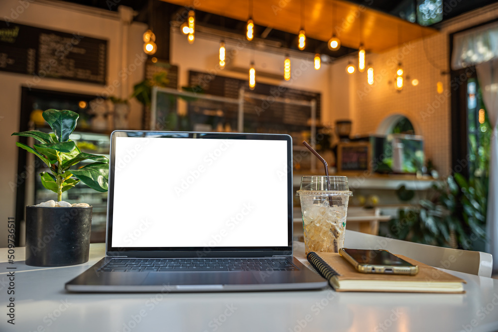 Mockup of laptop computer with empty screen with notebook,ice coffee and smartphone on table side the window in the coffee shop at the cafe,White screen