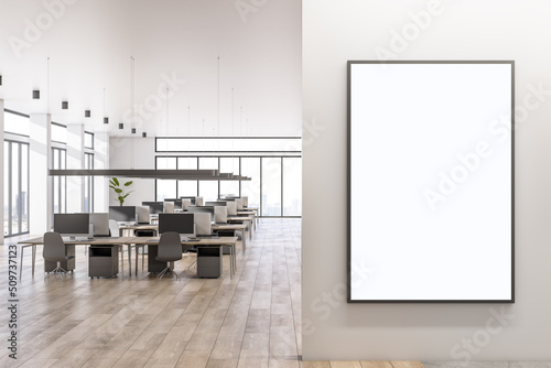 Blank white poster on light wall with place for your logo in spacious sunlit office area with cozy workspaces  high ceiling  panoramic windows with city view and wooden floor. 3D rendering  mockup