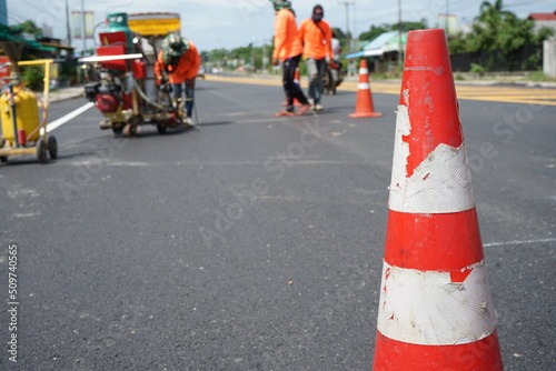 Red rubber cones are placed in the paved road.