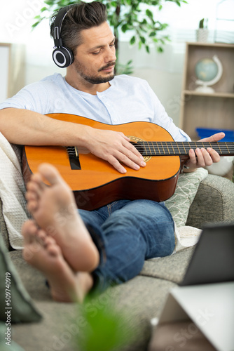 happy man playing the guitar on sofa at home
