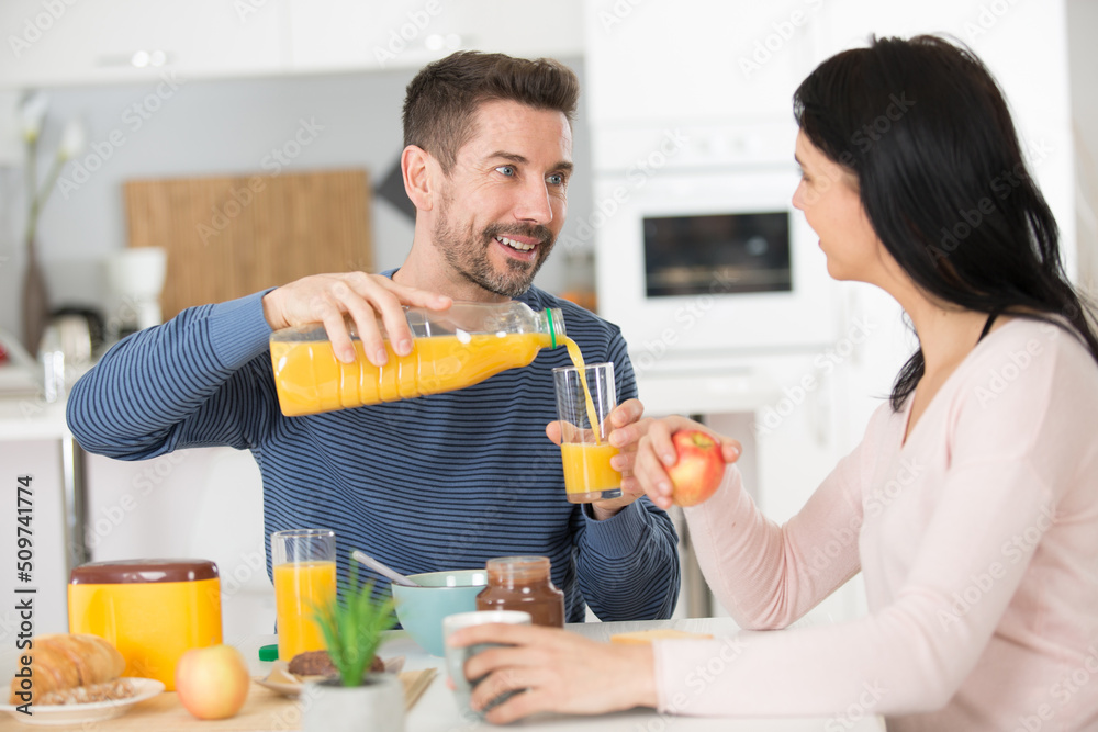 handsome positive man serving an orange juice to his wife handsome positive man serving an orange juice to his wife