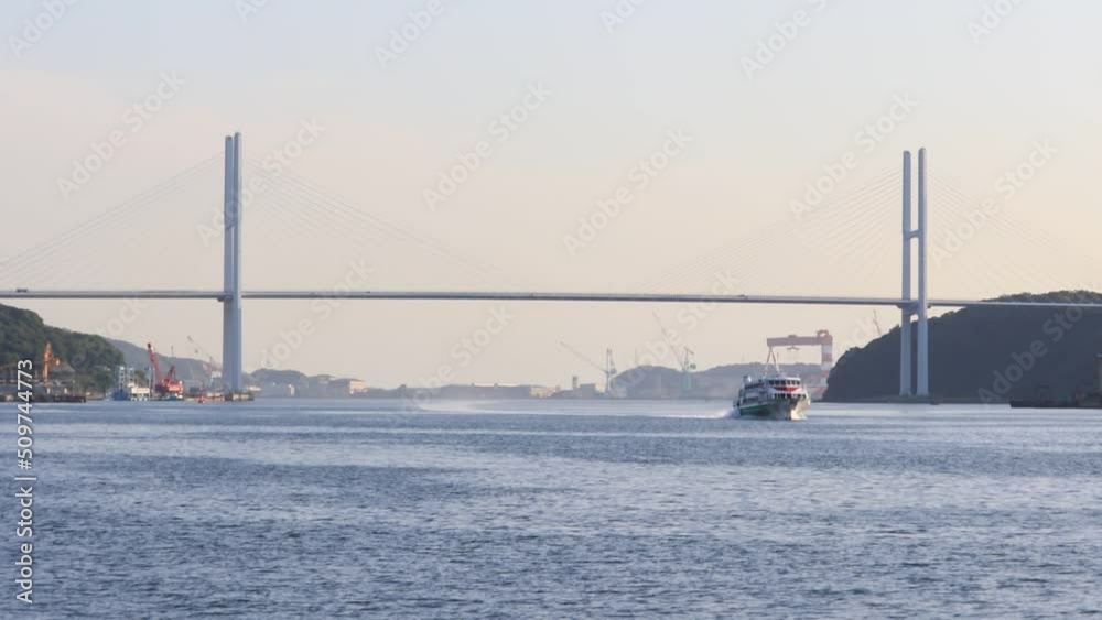 A pleasure boat coming back to the bay. Big bridge at the back. Nagasaki Japan A pleasure boat coming back to the bay. Big bridge at the back. Nagasaki Japan