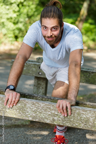 young fit man stretching legs outdoors doing forward lunge