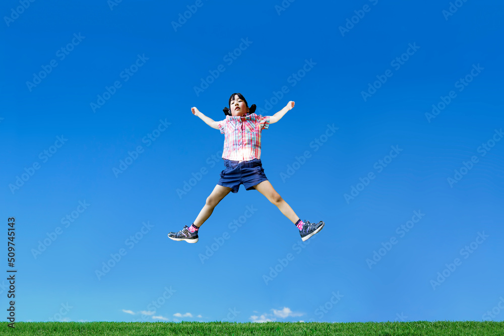 青空を背景に手足を広げジャンプする幼い女の子1人 青空を背景に手足を広げジャンプする幼い女の子1人