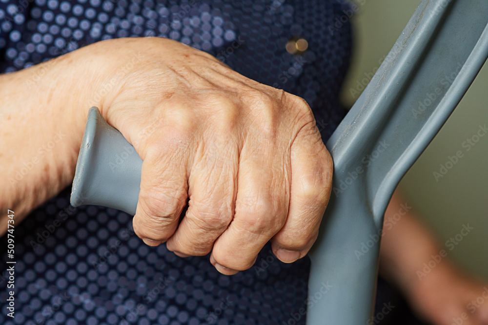 elderly woman leans on a crutch trying to get up. Hand close up