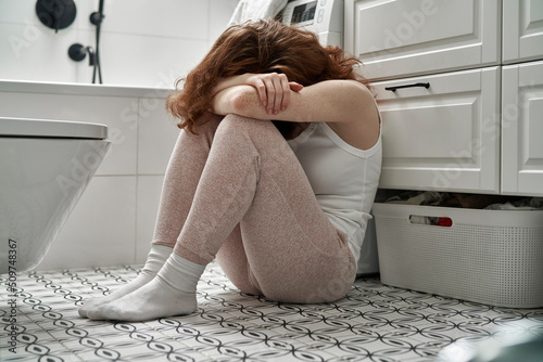 Quadro su tela Caucasian woman with problems sitting on the floor in the bathroom