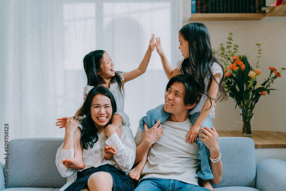 ソファに座って肩車をしてもらう子供達と両親