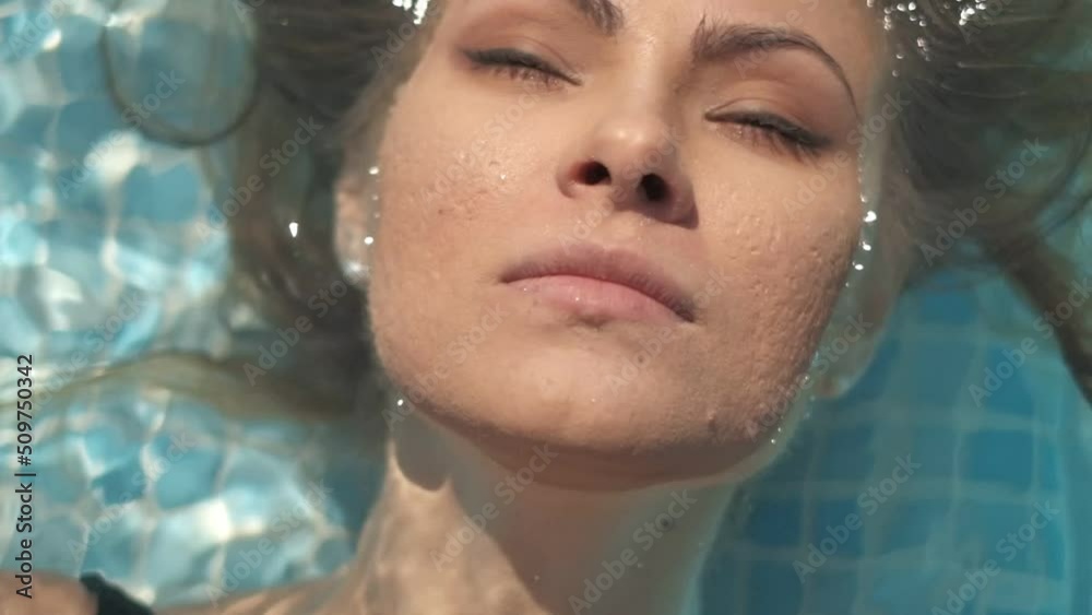 Closeups and details of waterdrops on young woman's skin wearing black swimsuite. Filmed in the outdoor swimming pool, slow motion. Closeups and details of waterdrops on young woman's skin wearing black swimsuite. Filmed in the outdoor swimming pool, slow motion.