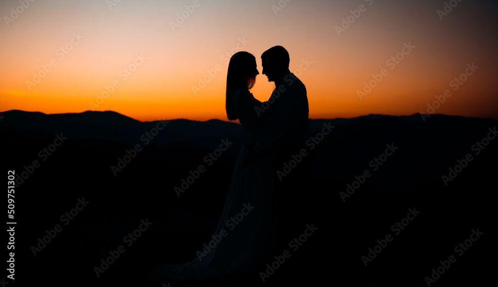 Silhouettes of a loving couple at sunset in the mountains