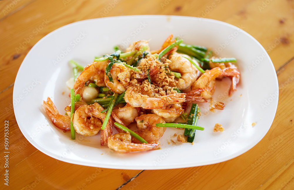 Fried shrimp with garlic and vegetables in white plate on wooden table, seafood. Top view. Fried shrimp with garlic and vegetables in white plate on wooden table, seafood. Top view.