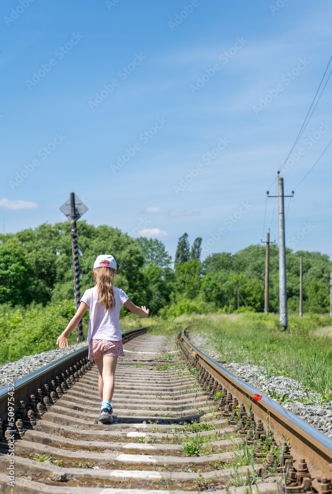 Rear view of little girl walking on railroad track against clear blue sky Rear view of little girl walking on railroad track against clear blue sky