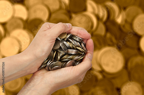Heap of coins in hand on blurred coins toned background