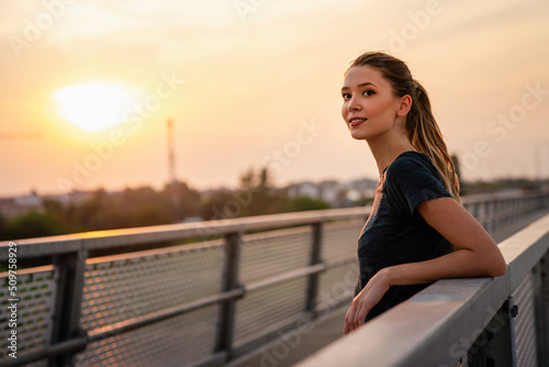 YYoung smiling satisfied fit woman resting after an active fitness training outdoors in city