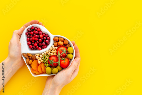 Foto Hands holding heart shaped dish full of healthy diet food