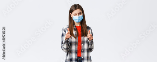 Coronavirus outbreak, leisure on quarantine, social distancing and emotions concept. You can dot it. Supportive young attractive female in medical mask pointing at camera, wink and congratulate photo