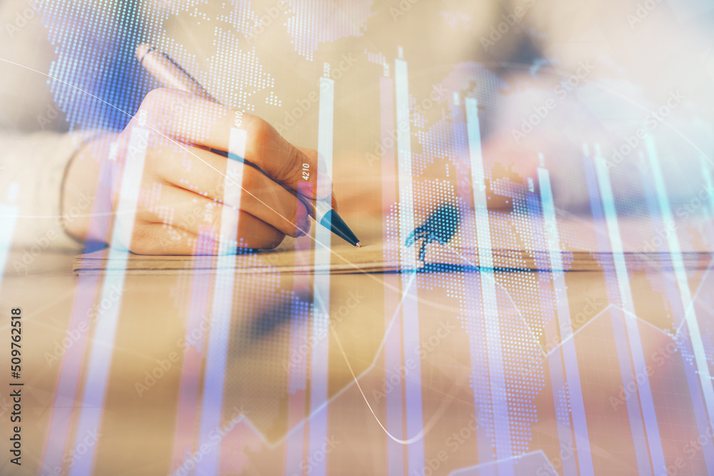 Hands writing information about stock market in notepad. Forex chart holograms in front. Concept of research. Multi exposure Hands writing information about stock market in notepad. Forex chart holograms in front. Concept of research. Multi exposure