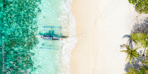View from above, stunning aerial view of a Bangka boat in front of a white sand beach bathed by a turquoise water. Coron Island, Palawan, Philippines. © Travel Wild