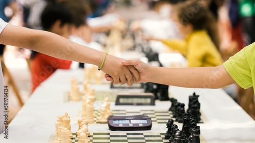 Handshake of the young people after the end of the chess match as a sign of sportsmanship and fair play. Concept of fairness, justice, equality, fidelity, honesty.