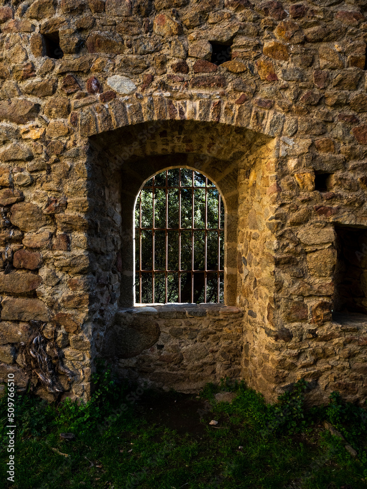 imagen detalle ventana en una muralla de piedra con una verja de hierro