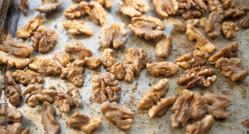 Roasted walnut lies on a metal baking sheet. Protein, healthy nuts, shortage of walnuts, more expensive snacks.