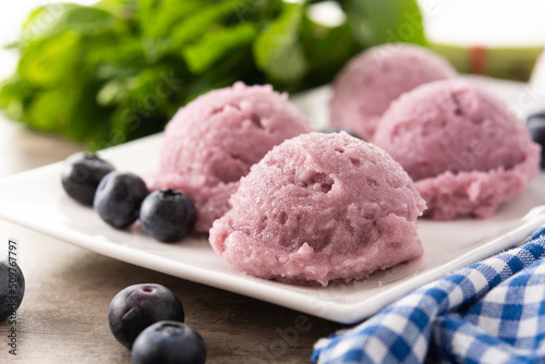 Blueberry ice cream scoops on wooden table 