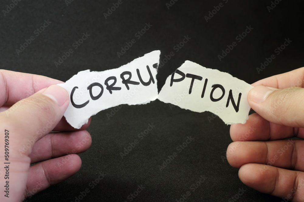 Stop and fight corruption concept. Human hand tearing a piece paper with written word corruption.