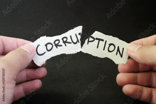 Stop and fight corruption concept. Human hand tearing a piece paper with written word corruption. photo