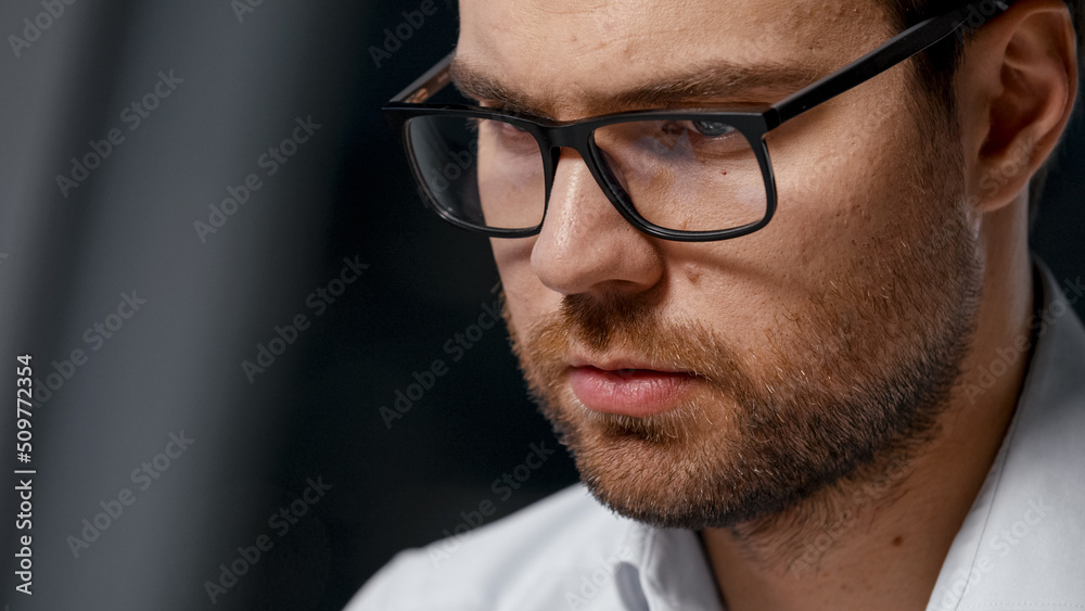 Working young businessman in eyeglasses at a laptop after hours in the evening Working young businessman in eyeglasses at a laptop after hours in the evening