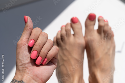 Beautiful female bright orange pink summer manicure and pedicure, perfect coating with gel polish on a white background