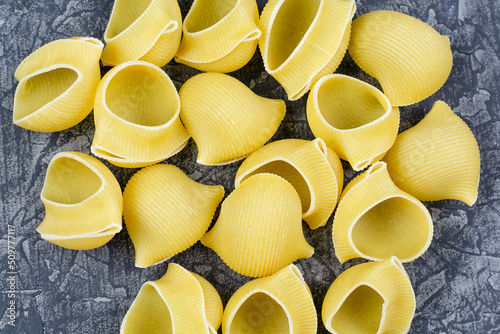 Large dry (raw) pasta lumakoni variety of durum wheat close-up on a black background. Pasta for stuffing and baking. photo