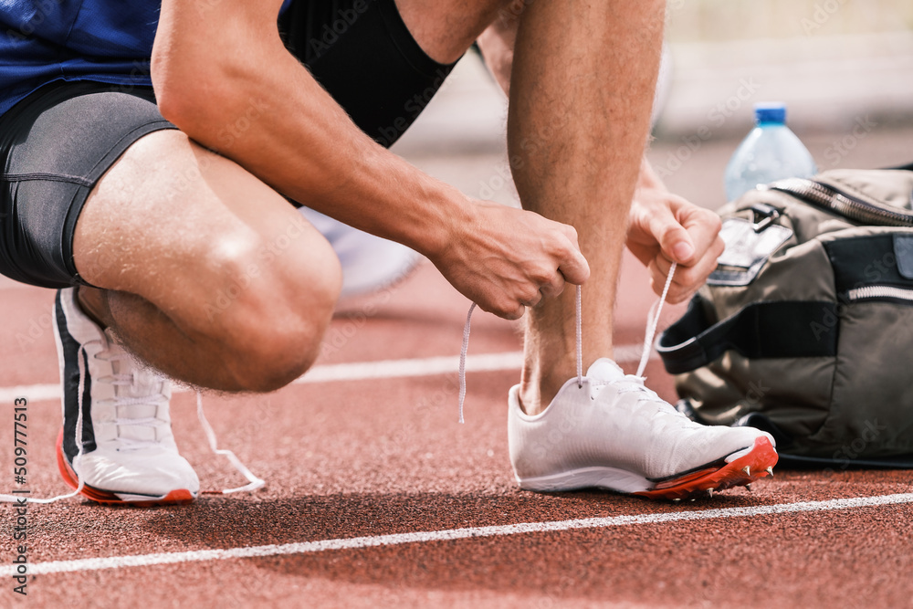 Un athlète sur une piste d'athlétisme en train de lacer ses chaussures de sport