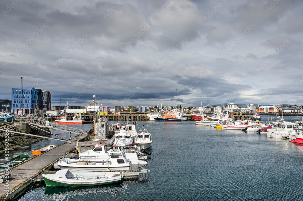 Hafnarfjörður, Iceland, May 8, 2022: boats in the town's harbour lit by the sun with a cloudy sky