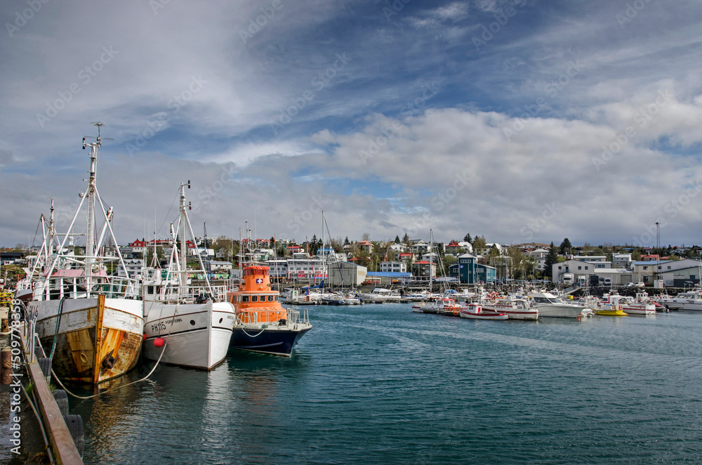 Hafnarfjörður, Iceland, May 8, 2022: colorful boats in the harbour with the equally colorful town in the background
