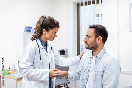Young female doctor hold hand of caucasian man patient give comfort  express health care sympathy  medical help trust support encourage reassure infertile patient at medical visit