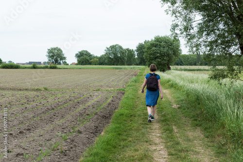 Attractive thirty year old woman in blue dress walking a trail through the Flemish countryside