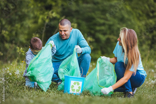 Mother and father teach their son to recycle plastic in recycling containers. They volunteer in a public park, clean up trash.