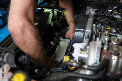 Car mechanic hands replacing intercooler on a car engine. Mechanics workshop. photo