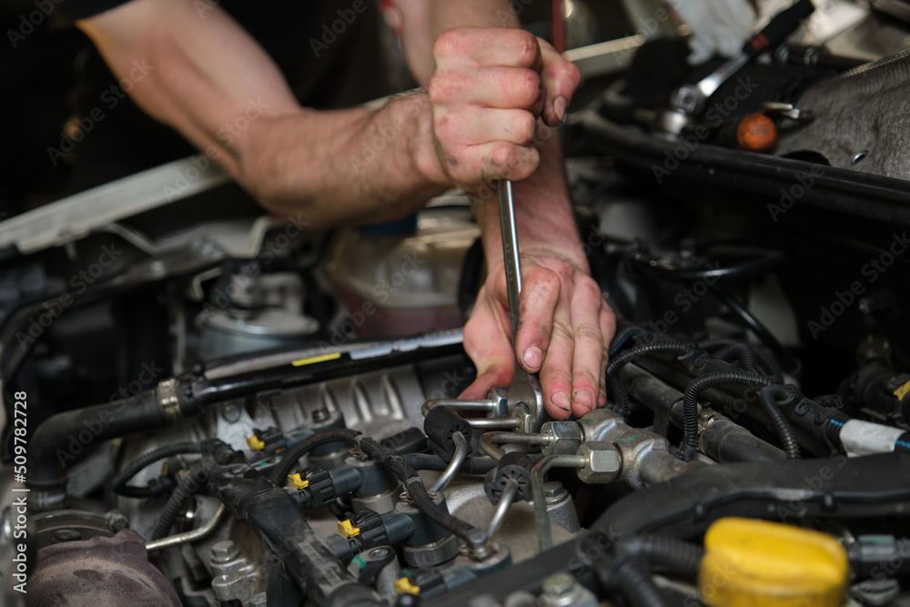 Close up of car mechanic hands removing fuel injectors in engine room checking dust and test pressure in maintenance process. Close up of car mechanic hands removing fuel injectors in engine room checking dust and test pressure in maintenance process.