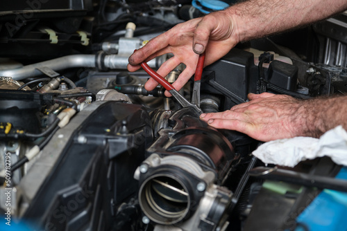 Car mechanic hands replacing engine throttle body. Mechanics workshop. © Ladanifer