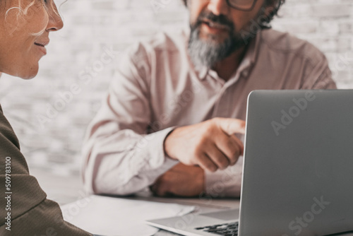 Close up of couple working together on laptop computer. Man show at woman notebook display as a consultant. Job and agreement explanation business concept. People at the office. Seller and buyer