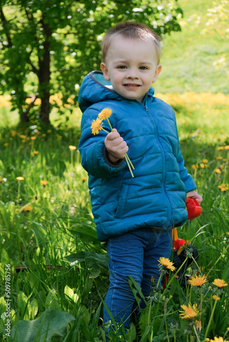 Cute toddler boy holding spring flowers in his hand.