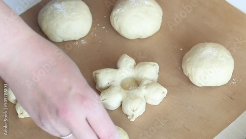 The woman shapes the dough into a flower shape. Preparing donuts in the form of a flower. Close-up photo