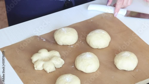 The woman shapes the dough into a flower shape. Preparing donuts in the form of a flower. Close-up. photo