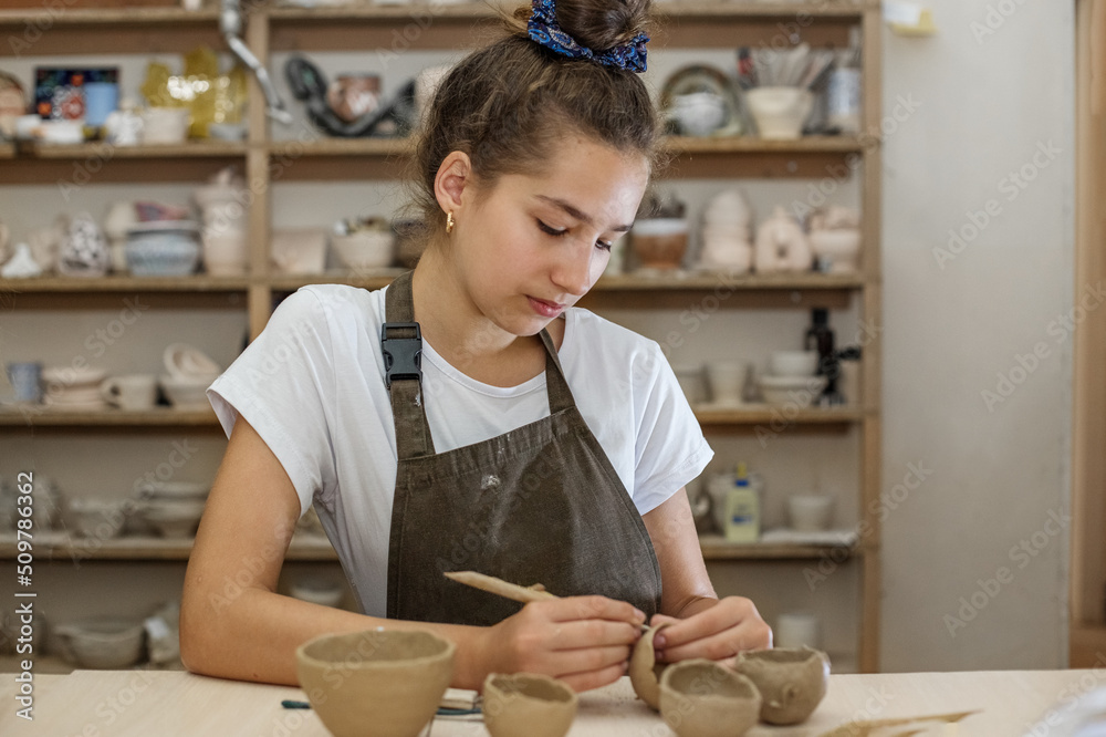 Beautiful teenage girl playing with modeling clay in pottery workshop. Craft and clay art. Vertical Beautiful teenage girl playing with modeling clay in pottery workshop. Craft and clay art. Vertical