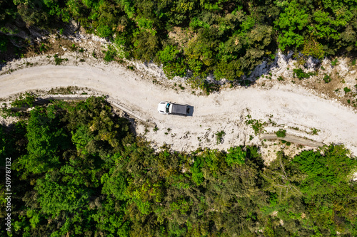 Aerial of Offroad truck driving on a narrow mountain road through the forest photo